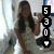 A pixelated image shows a person with long dark hair holding an object near their face, next to vertical black blocks displaying white numbers 5, 3, 0, and T.