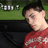 A pixelated image shows a person in a red shirt with white patterns, resting their head on a dark surface against a green background with white rectangular shapes.