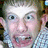 Pixelated image of a person with light hair and blue eyes wearing a checkered shirt, next to black background with white text.