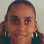 A person with dark hair pulled back, wearing large hoop earrings and a dark top, smiling in four -aligned