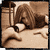 A 50x50 pixel animated contact sheet showing three sequential frames of a woman with long brown hair lying on her side, resting her head on an arm or pillow in sepia-toned colors.
