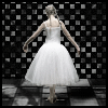 A ballerina in a white tutu viewed from behind, standing on a checkered floor with a black-and-white background
