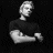Pixelated grayscale icon of a person in profile view with arms crossed, set against a black background with scattered white dots.