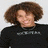 A static image shows a person with curly brown hair in a black shirt on the left, and two people standing together on the right.