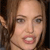 A pixelated close-up of a person's face with light brown hair, visible eyes, nose, mouth showing teeth, and a neutral expression against a dark background.