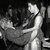 Black-and-white pixelated image shows two figures in close physical contact against a dark background with visible pixelation and grayscale tones.