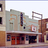 Pixelated image of a building facade with multiple windows and a flagpole, showing architectural details and color variations.