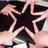 A black star with a pink outline is held by hands in four showing slight movement