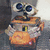 Pixelated robot with large blue eyes, orange body, and white accents on arms against a gray background.