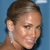 Pixelated close-up of a person with brown hair tied back, wearing a white earring, against a solid blue background.