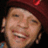 Pixelated image of a person with red headwear and ear piercings on left, set against purple background with pixelated text.