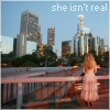 Pixelated cityscape with skyscrapers, a bridge, and a woman in a light dress standing on the bridge, with text reading 'she isn't real' at the top.