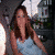 A 50x50 pixel animated contact sheet showing three frames of a woman with long brown hair in a light blue sleeveless top against an outdoor background with buildings and greenery.