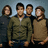 Four people stand in a against a light blue background, with green text reading "Dance Dance" and "I Love FOB! This Ain't a Scene It's an Arms Race" on purple