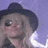 Pixelated close-up of a person wearing a dark wide-brimmed hat against a light purple background with white highlights.