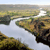 Pixelated landscape with water, green and brown terrain, and a light sky, rendered in low-resolution style.