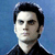 Pixelated portrait of a person with dark hair against a blue background, wearing a dark collared shirt.