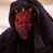 Static pixelated image of a red-skinned character with horns wearing dark hooded clothing against a light background.