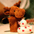 Brown plush moose and white duck with red spots stand on a light surface against blurred background.