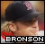 Pixelated image of a person wearing a dark cap with pink accents, red clothing, and white text reading BRONSON at the bottom.