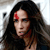A pixelated close-up of a person with long dark hair, a red mark on the forehead, and a dark top, set against a light background.