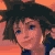 Pixelated close-up of a character with dark hair and blue eyes against an orange background, wearing a dark blue outfit.