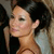 A pixelated close-up of a person with dark hair, light skin, and a neutral expression, wearing a brown strap over one shoulder.