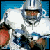 Pixelated football player in silver helmet and white jersey holding a brown football, with blue background showing motion blur effects.