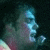 Pixelated profile image of a person with blue-toned skin against dark background, next to brown with white text