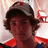 A pixelated image of a person with curly hair wearing a dark cap and red-collared shirt, next to bright pink text reading 'connor, i love you and miss you so much<3'.