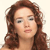 Pixelated close-up of a person with long brown hair, light skin, and neutral expression against a plain background.