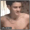 A shirtless man with dark hair and a silver chain necklace appears in three showing torso movement, wearing white underwear and black pants