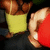 A pixelated image shows two figures in close physical contact, one in a yellow top and brown hair, the other in a red top with light skin, against a dark background.