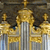 Golden architectural structure with columns and decorative elements against a dark background.