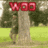 A pixelated static image shows a red 'WOO' text above a tree trunk with green grass and blurred foliage background.