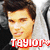 Pixelated close-up of a person with dark hair and light skin, wearing a white garment with a red text overlay reading "TAYLOR".