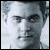Pixelated grayscale portrait of a person with short hair, neutral expression, and visible eyes, nose, and mouth against a light background.
