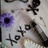 Pixelated image with blue background displaying white text 'I XOXO himx33' and scattered black star-like symbols on a light gray surface.