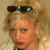 Static pixelated image of a person with sunglasses on head, blonde hair, and red lips against beige background.