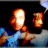 Pixelated figure with glowing orange and white face holding a smaller glowing object against dark background, blue and gray lower section.