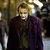 Pixelated static image of a person in dark clothing with a purple garment, standing against a blurred background with light and dark tones.