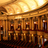 Pixelated image of a theater facade with columns under a bright sky, rendered in warm brown and orange tones.