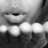 Black-and-white close-up of a person's mouth and teeth with eyes partially visible, showing subtle facial movement across frames.