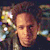 Pixelated image of a person with light skin tone, dark hair, and a neutral expression, surrounded by colorful abstract shapes and light effects.
