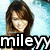 Pixelated image of a person with long brown hair and light skin, smiling, with the text "miley" in bold white letters on a black background at the bottom.
