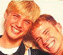 Static pixelated image of two smiling people with light brown hair in close proximity against a plain background.
