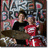 Two figures in a red and white outfit pose with a drum set against a graffiti-covered wall, one figure's head slightly shifted between frames.