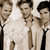 Three pixelated figures in light-colored suits with dark ties stand side-by-side against a light background, each with distinct hairstyles and facial features.
