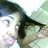 Pixelated image of a person with dark hair and light skin, wearing a dark top, against a light background with green and blue tones.