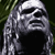 Pixelated grayscale icon of a hooded figure with long hair, dark background, and visible dithering patterns.